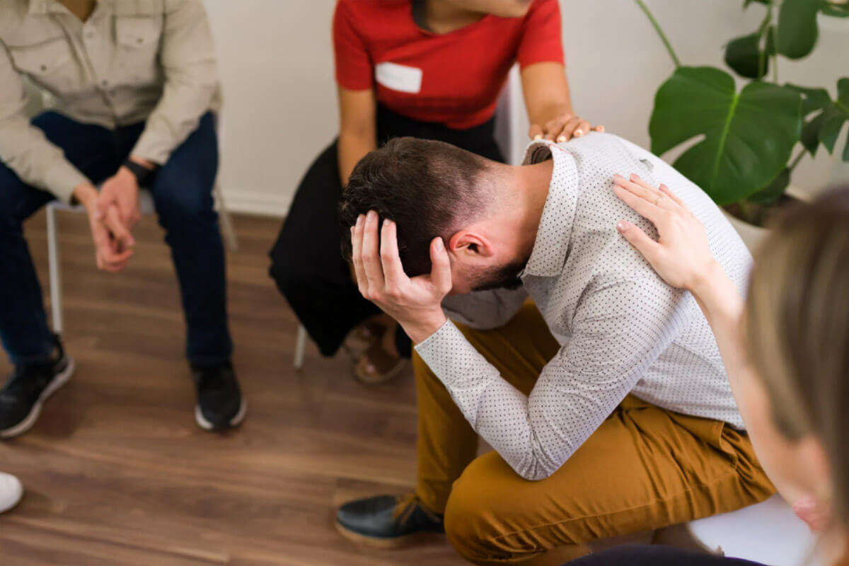 A person receiving support from others in a group setting, representing compassion, connection, and shared healing in recovery.