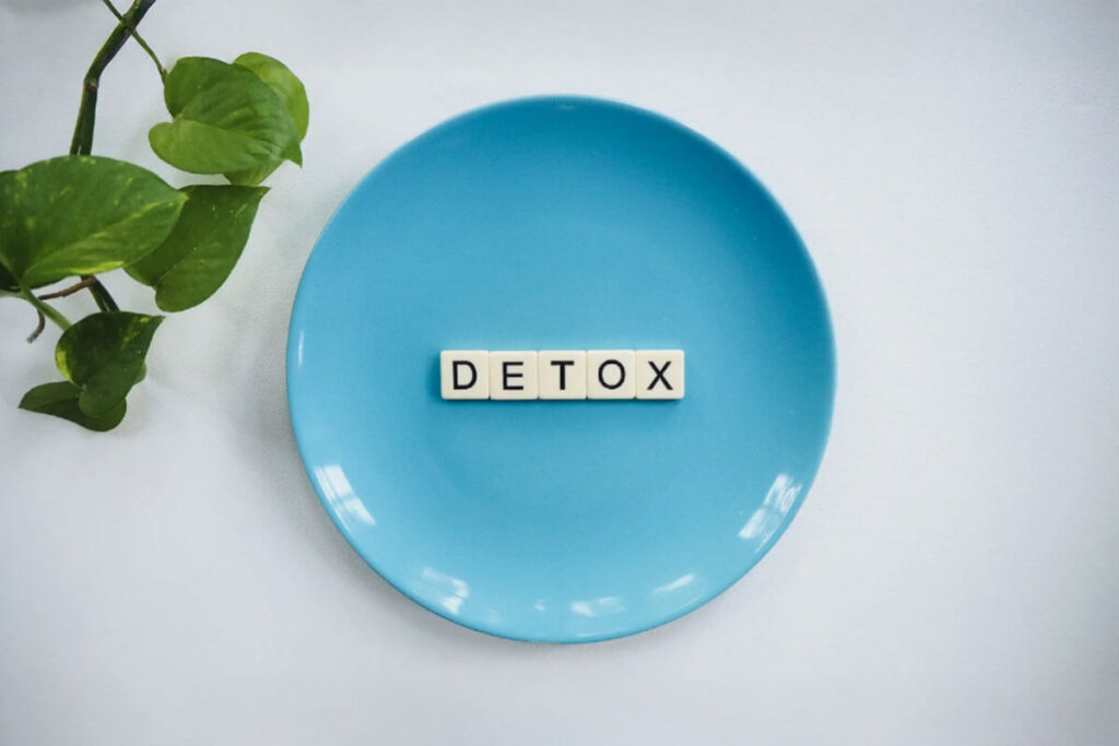 The word “Detox” spelled out with letter tiles on a blue plate, symbolizing the detox process.